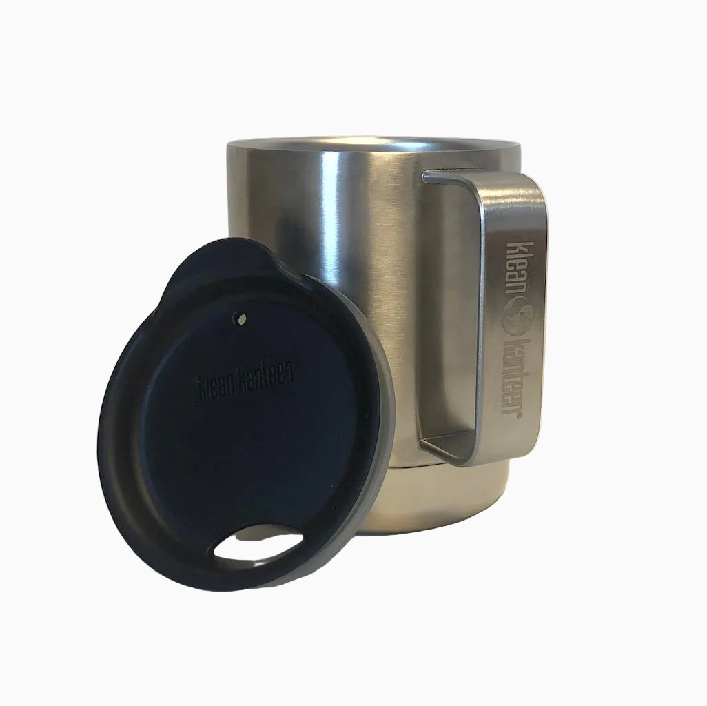 Klean Kanteen NOLS Camp Mug featuring brushed stainless steel finish with black splash-proof lid and sturdy handle, displayed on white background. The 12 oz vacuum insulated mug shows its durable construction and sleek design for outdoor use.